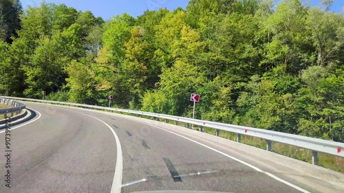 Driving at dawn on a beautiful and quiet road with breathtaking views of beautiful mountains. View from the driver's side through the windshield.