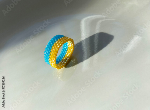 Blue yellow beaded ring over a glossy background. photo