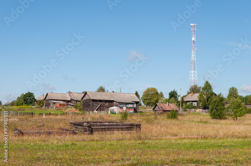 Summer country landscape, russian village with old log houses and cell tower, Kostroma region, Russia