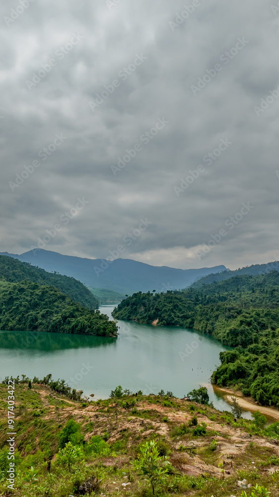 A serene mountain lake surrounded by lush greenery under a cloudy sky, perfect for concepts of tranquility and nature retreats A serene mountain lake surrounded by lush greenery under a cloudy sky, perfect for concepts of tranquility and nature retreats