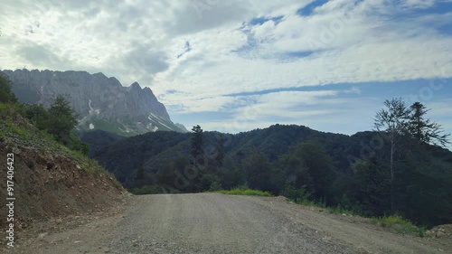 Summer road in the green mountains. View from the car on a winding mountain road.
