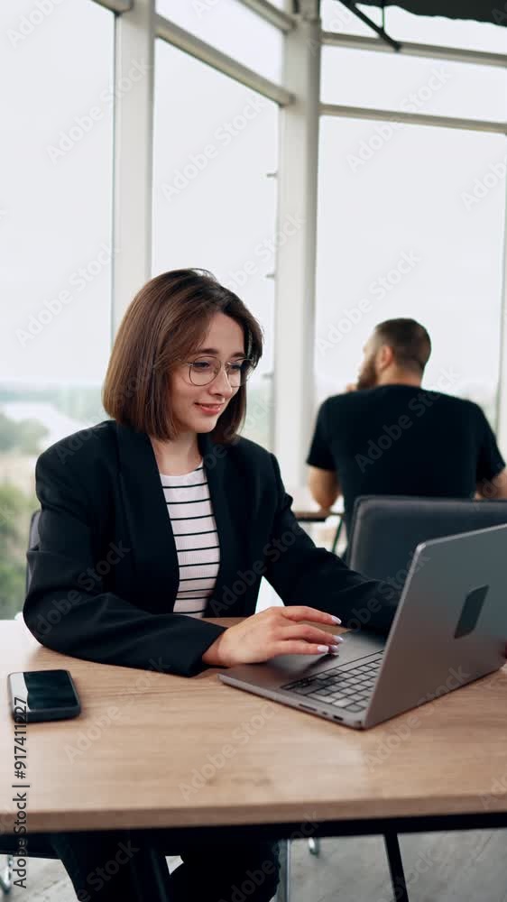 Resilient Caucasian woman working in the office at laptop. Portrait of a modern confident lady at work. Vertical video. Resilient Caucasian woman working in the office at laptop. Portrait of a modern confident lady at work. Vertical video.