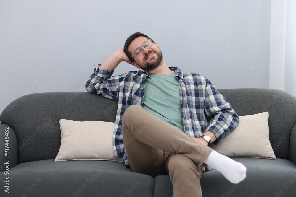 Smiling man relaxing on sofa at home Smiling man relaxing on sofa at home