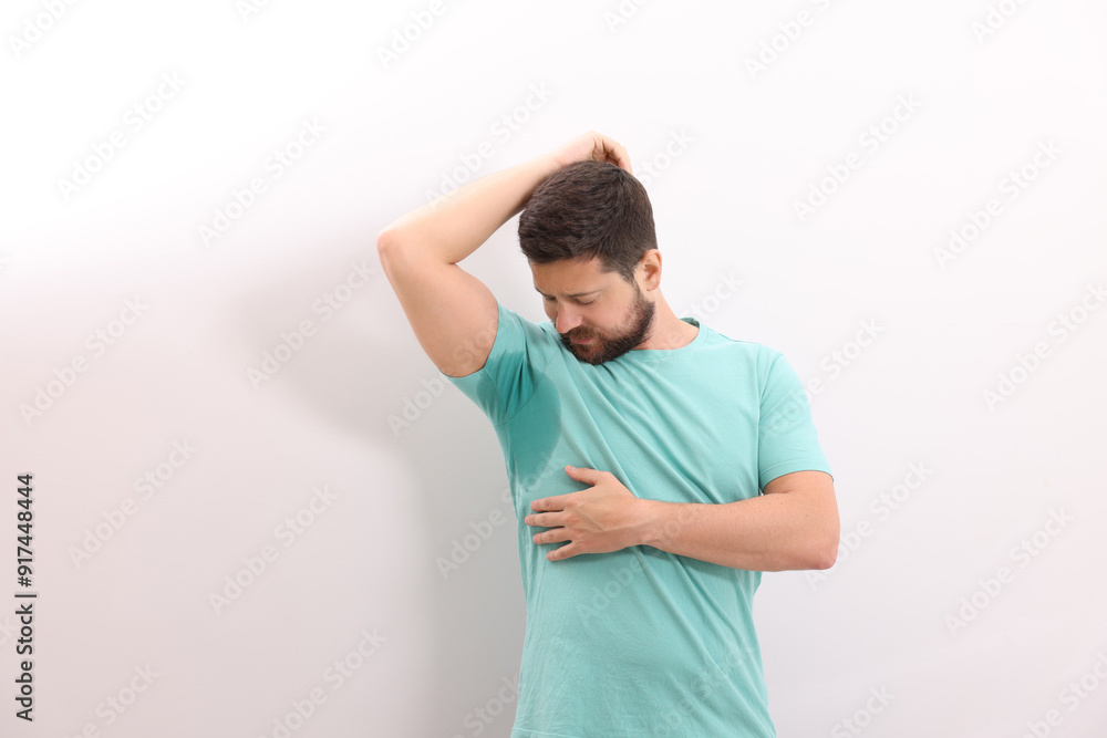 Emotional man in t-shirt before using deodorant on white background Emotional man in t-shirt before using deodorant on white background