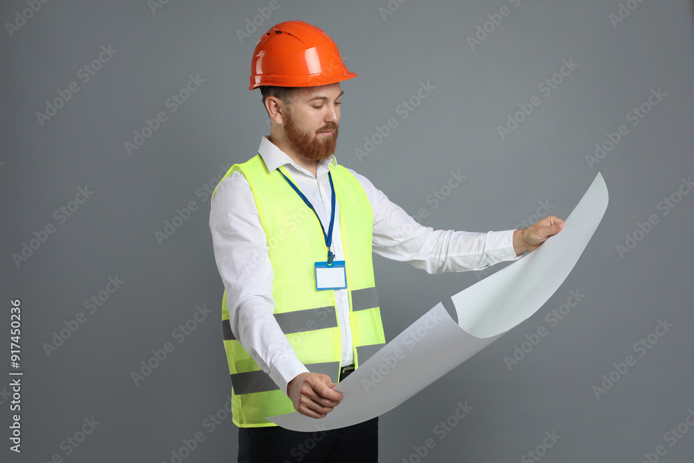 Engineer in hard hat with draft on grey background Engineer in hard hat with draft on grey background