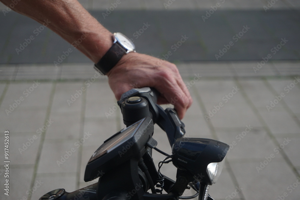 Obraz premium Hand von Mann auf Fahrrad in Fußgängerzone in Kleinstadt bei Sonne am Abend im Sommer