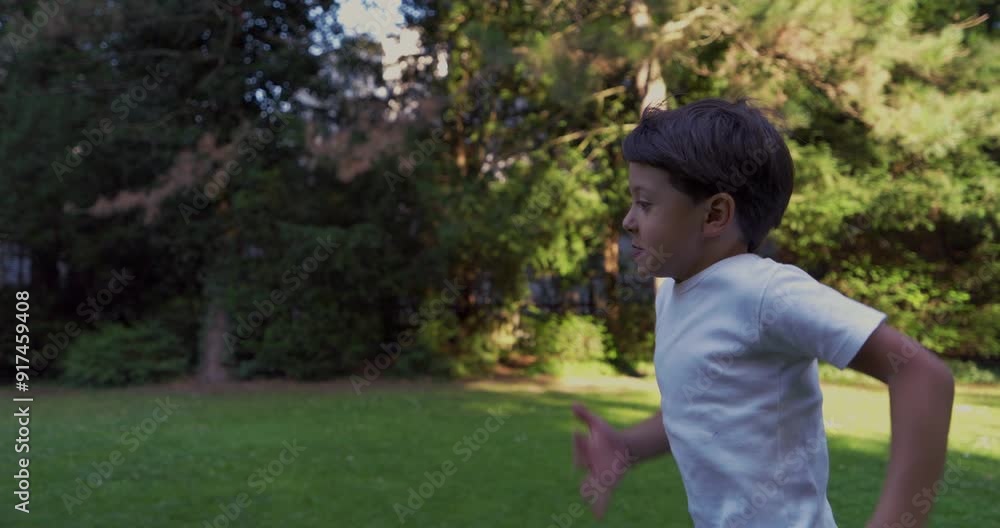 Young boy running in a park, wearing a white shirt, with a determined expression, surrounded by greenery, enjoying an energetic moment outdoors on a sunny day Young boy running in a park, wearing a white shirt, with a determined expression, surrounded by greenery, enjoying an energetic moment outdoors on a sunny day