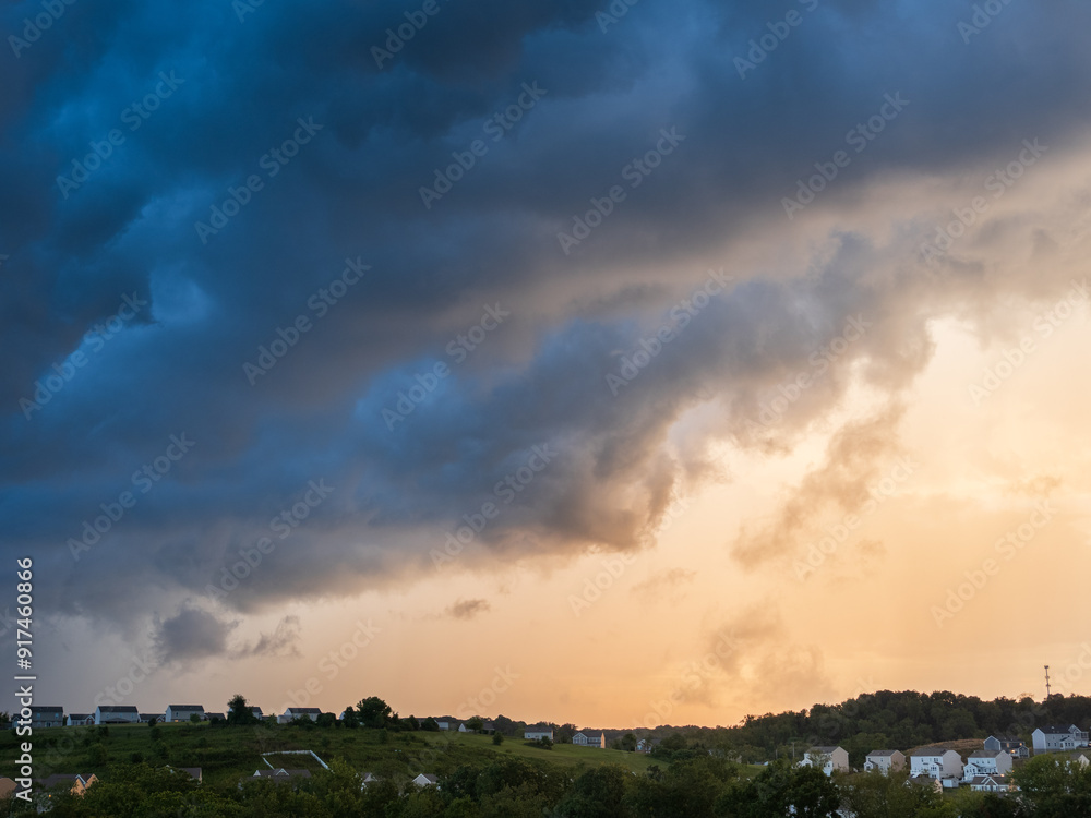 Dramatic storm clouds hanging over a US residential neighborhood with bright gap in the sky on a summer evening. Dramatic storm clouds hanging over a US residential neighborhood with bright gap in the sky on a summer evening.