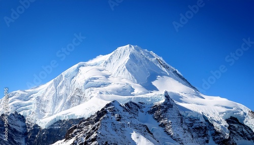 A very tall mountain covered in snow rises against a clear sky background, creating a striking natural winter scene.