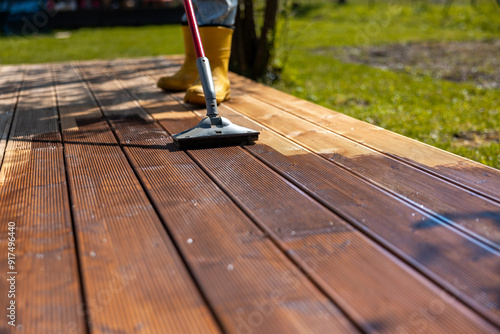 Canvas Print Person applying stain to a wooden deck in a backyard, focusing on maintenance an