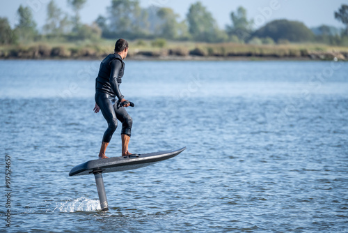 Schilderij op canvas A man glides effortlessly on an electric hydrofoil surfboard