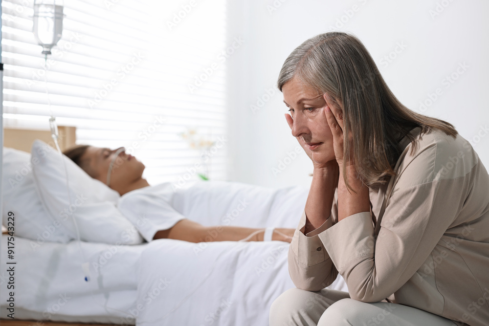 Coma patient. Sad mature woman near her unconscious son in hospital Coma patient. Sad mature woman near her unconscious son in hospital