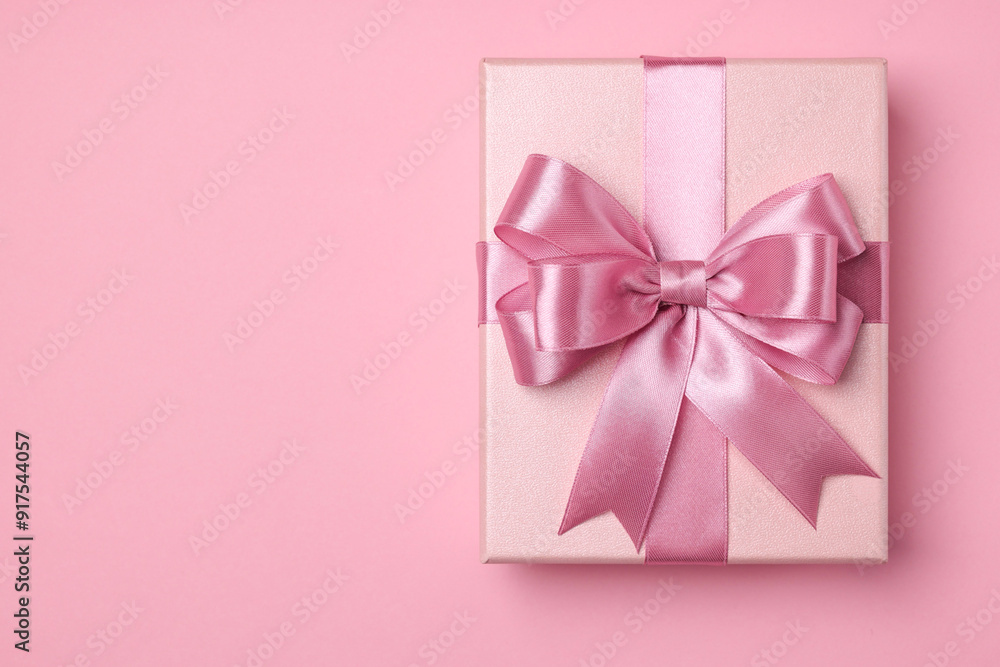 Beautiful gift box with color bow on pink background, top view. Space for text Beautiful gift box with color bow on pink background, top view. Space for text