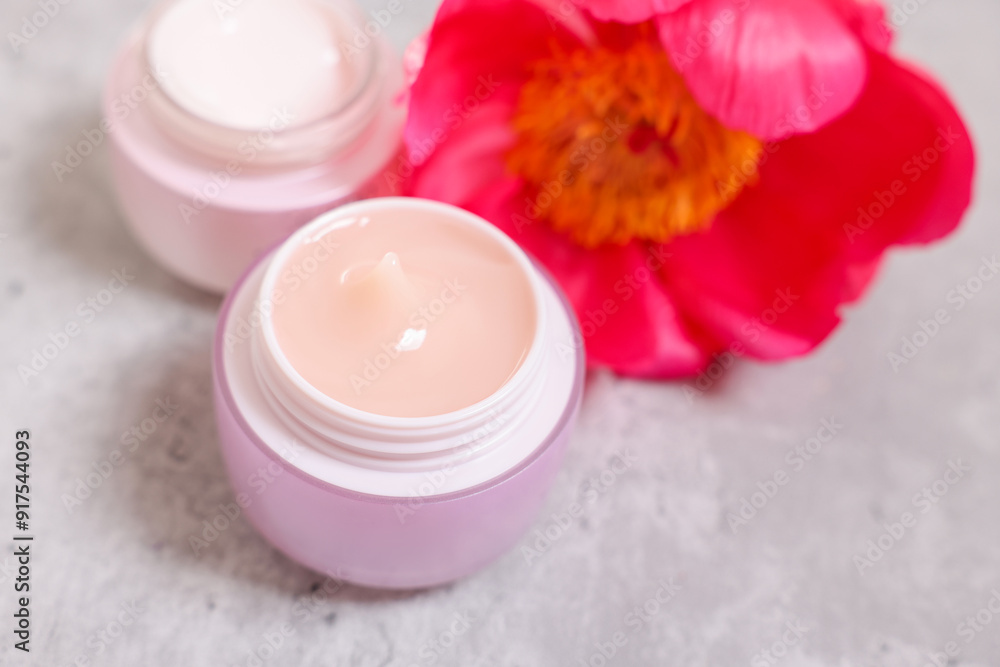 Jars of creams and peony flower on gray table, closeup Jars of creams and peony flower on gray table, closeup