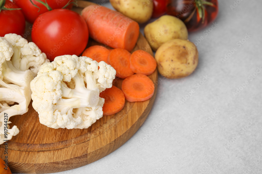Cooking vegetable stew. Cauliflower, tomatoes, carrot and potatoes on light grey table, space for text Cooking vegetable stew. Cauliflower, tomatoes, carrot and potatoes on light grey table, space for text