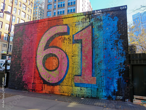 Obraz na płótnie A colorful mural of the number 61 on a brick wall. The mural is bright and colorful, with a rainbow of colors. The number 61 is written in a bold, graffiti-style font w salonie