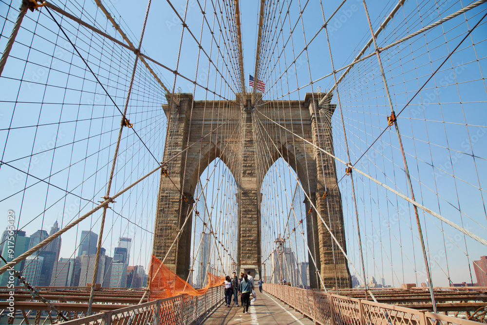 Fototapeta premium Walking the Brooklyn Bridge over the river and into Manhattan in New York USA on a spring day