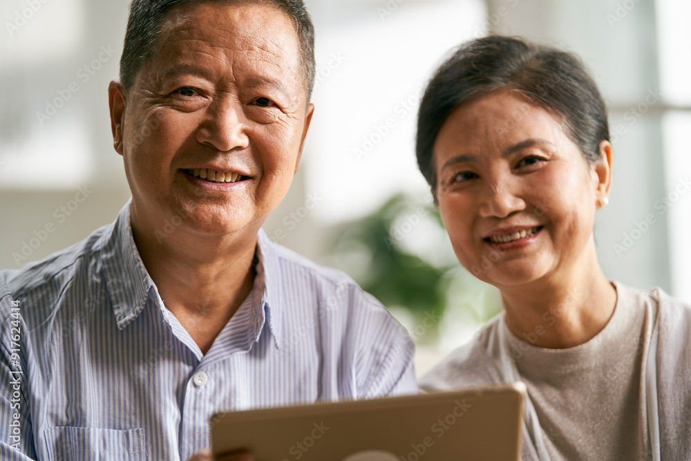 happy senior asian couple using digital tablet together at home