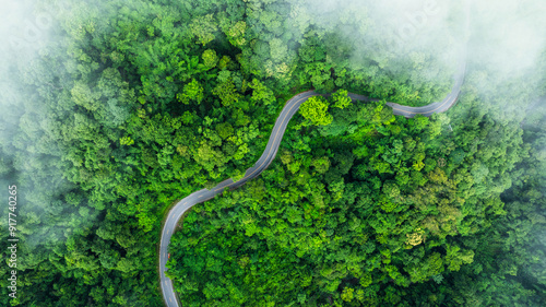 Fototapeta Naklejka Na Ścianę i Meble -  Aerial view of a road in the middle of the forest , road curve construction up to mountain	

