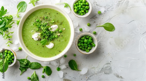   Green pea soup in a bowl with mint garnish and surrounded by small bowls of green peas on a white surface