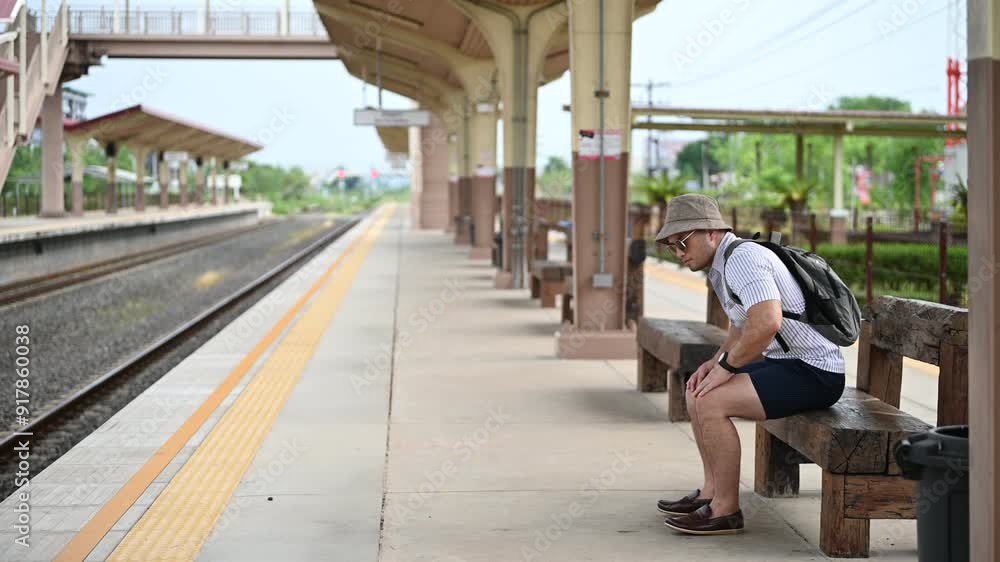 Handsome young man with a backpack uses the phone while standing near the railroad train on the platform,Tourism and travel in the summer. Vacations for the student. Handsome young man with a backpack uses the phone while standing near the railroad train on the platform,Tourism and travel in the summer. Vacations for the student.