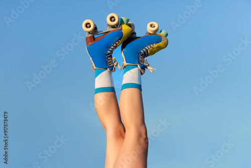 Girl with roller skates raised against a blue sky background