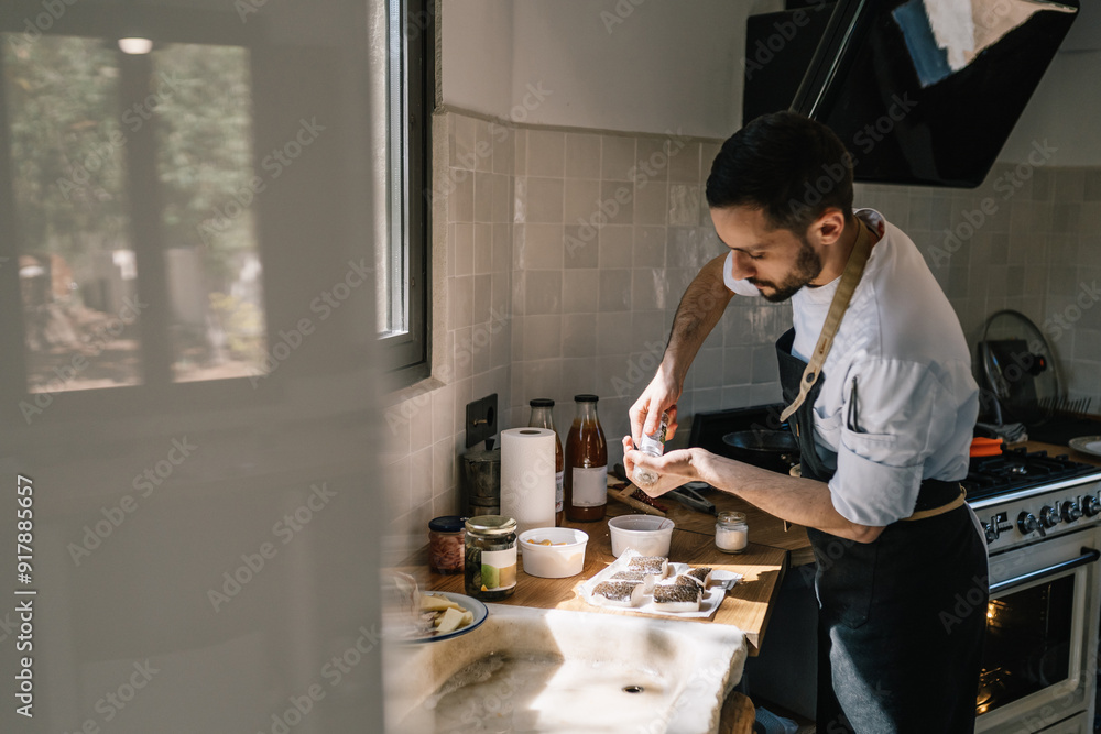Private chef preparing fresh fish fillets in a sunlit kitchen