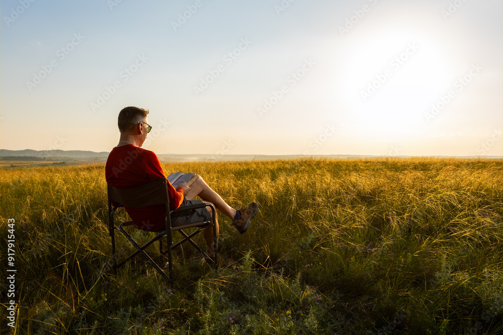 man sitting on an outdoor chair at nature and enjoying reading a book. man sitting on an outdoor chair at nature and enjoying reading a book.