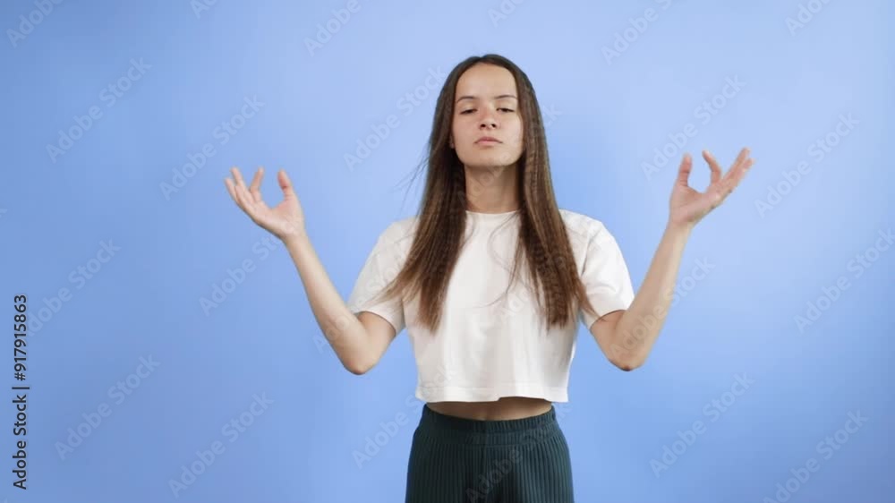 Teenager shows a sign of calm and tranquility, portrait on blue background, young cute emotional student, smiling youth with curly hair, happy and stylish girl, joyful and positive. Teenager shows a sign of calm and tranquility, portrait on blue background, young cute emotional student, smiling youth with curly hair, happy and stylish girl, joyful and positive.