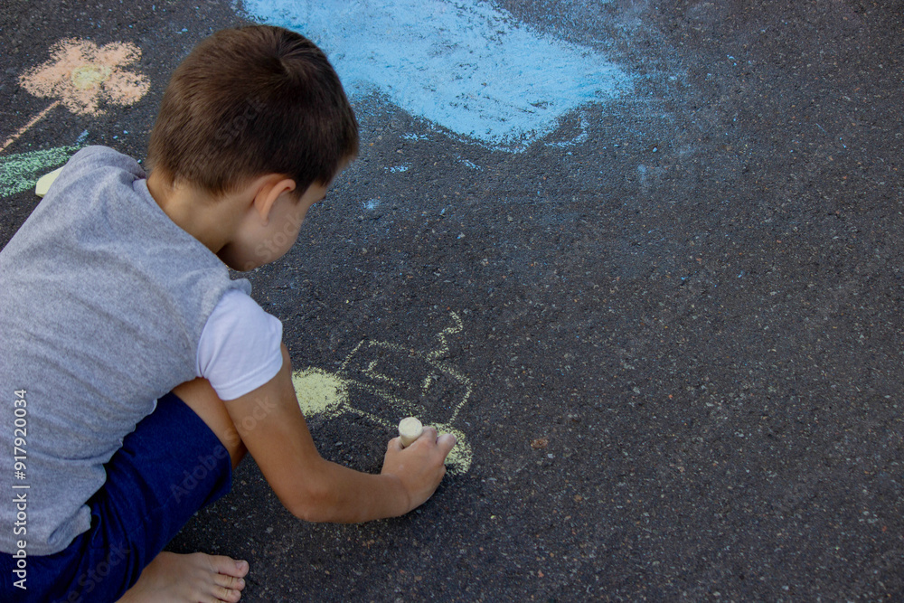 Naklejka premium the boy draws with chalk on the asphalt. Selective focus