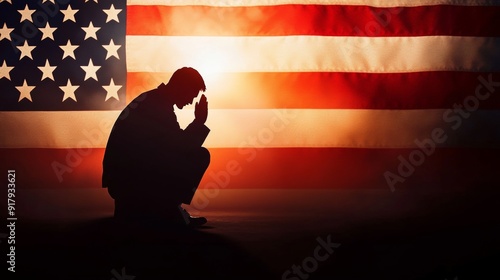 Silhouette of a man praying in front of American flag. Faith and patriotism concept