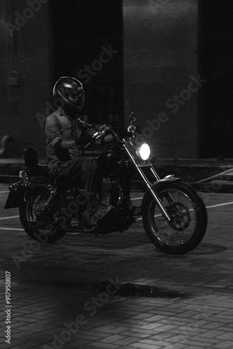 a man on a red chopper motorcycle. guy on a bike at night.