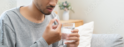 Quadro em tela Young man taking painkiller and drink water to healing from cold flu