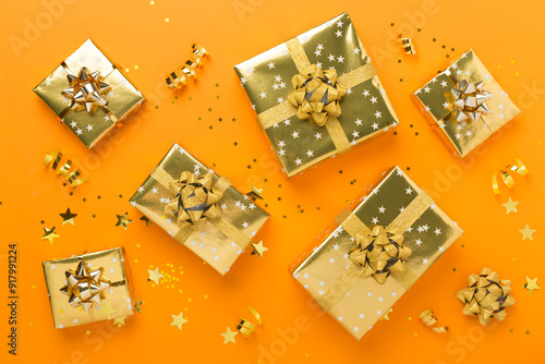 Golden gift boxes and confetti on color background, top view