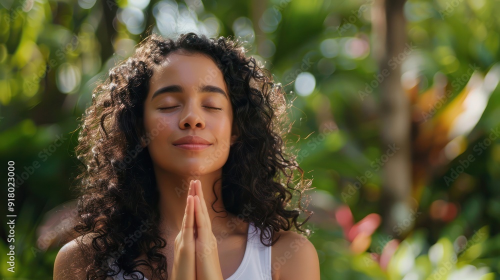 Calm young Hispanic woman holding hands in namaste meditating doing yoga breathing exercises with eyes closed feeling peace of mind, mental balance standing in green nature tropical park Calm young Hispanic woman holding hands in namaste meditating doing yoga breathing exercises with eyes closed feeling peace of mind, mental balance standing in green nature tropical park