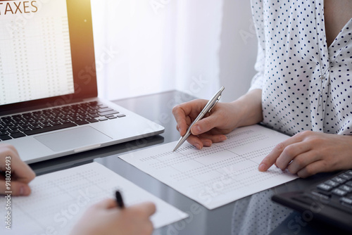 Two accountants use a laptop computer for counting taxes or revenue balance. Business, audit, and taxes concepts photo