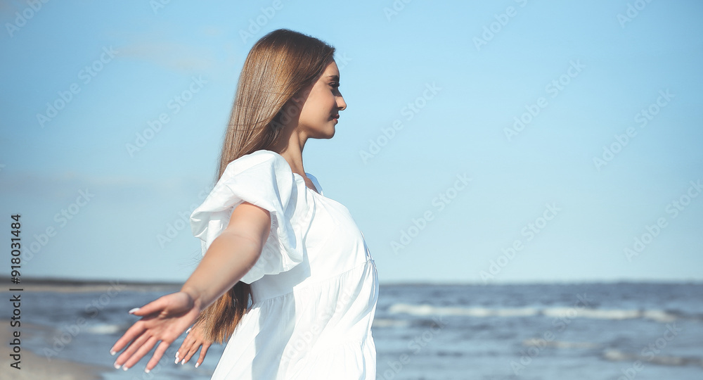 Happy, beautiful woman on the ocean beach standing in a white summer dress, open arms Happy, beautiful woman on the ocean beach standing in a white summer dress, open arms