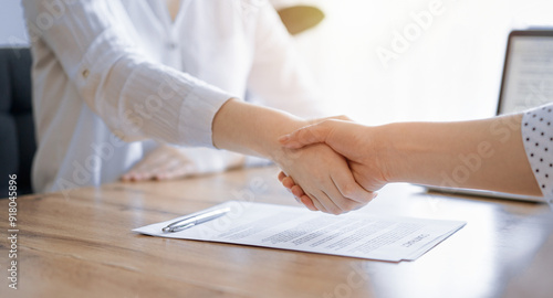 Business people shaking hands above contract papers just signed on the wooden table, close up. Lawyers at meeting. Teamwork, partnership, success concept