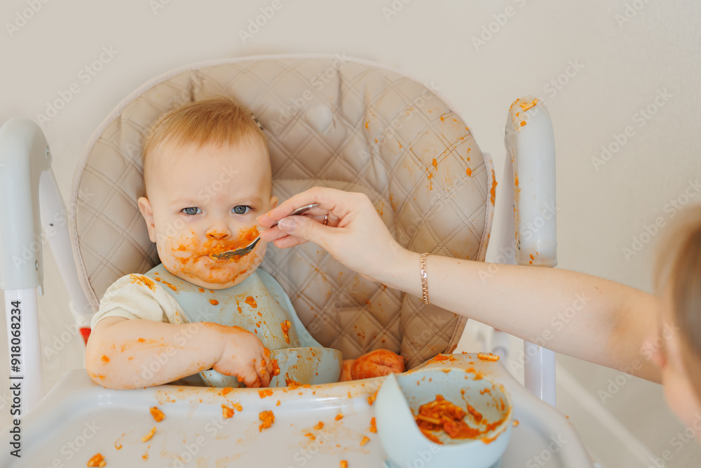 Young parent mom feeding pasta to baby boy at dining high chair. Young parent mom feeding pasta to baby boy at dining high chair.