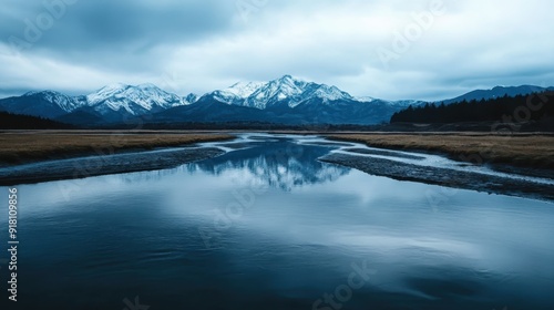 This striking photograph captures the serene reflection of a snow-capped mountain range in a calm lake, creating a breathtaking scene that highlights the tranquility and beauty of nature.