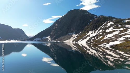 Discover the stunning view of a serene lake reflecting the majestic snowcapped mountains in Norways Alps, a perfect spot for travel enthusiasts and nature lovers, Hardangervidda Geiranger photo