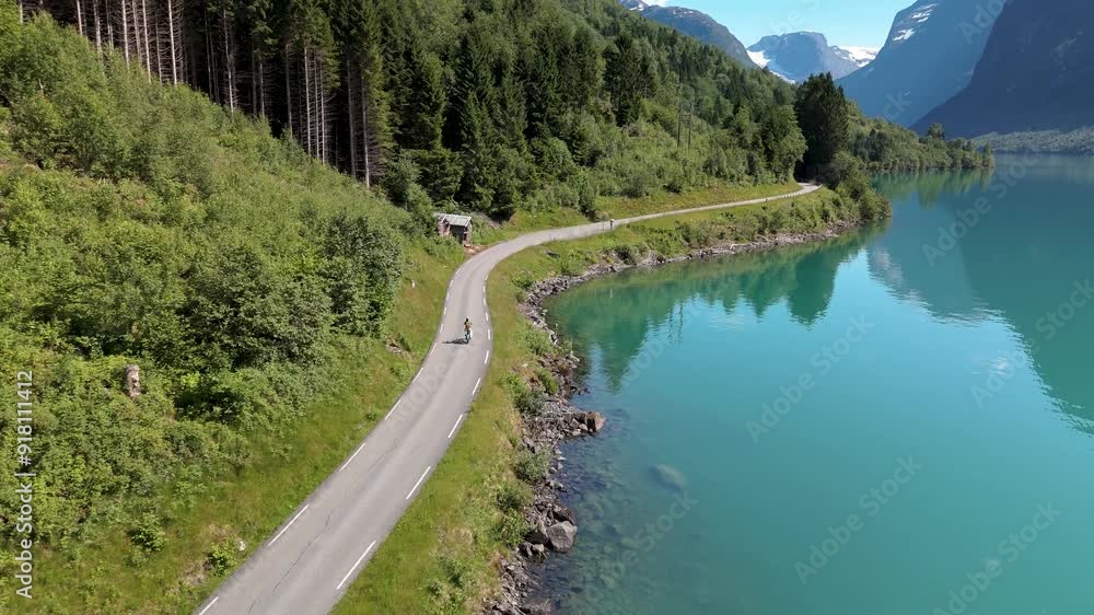 Enjoy breathtaking aerial views of Lovatnet, Norway coastal road, featuring vibrant blue waters and lush landscapes. A woman bicycle around the turqouse colored lake Enjoy breathtaking aerial views of Lovatnet, Norway coastal road, featuring vibrant blue waters and lush landscapes. A woman bicycle around the turqouse colored lake