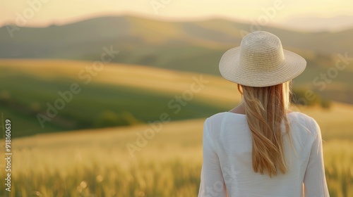 Woman in a Straw Hat Enjoying a Serene Sunset Over Rolling Hills