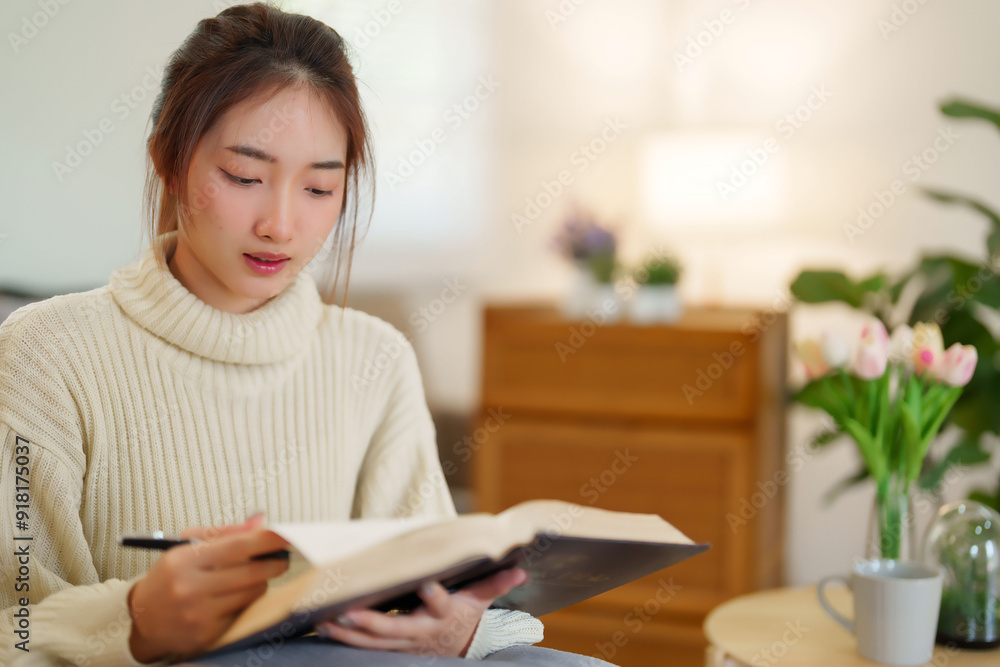 Young asian women in sweater opening the book to reading and learning about education for writing knowledge while relaxation and doing activity to spending time with slow life lifestyle at home Young asian women in sweater opening the book to reading and learning about education for writing knowledge while relaxation and doing activity to spending time with slow life lifestyle at home
