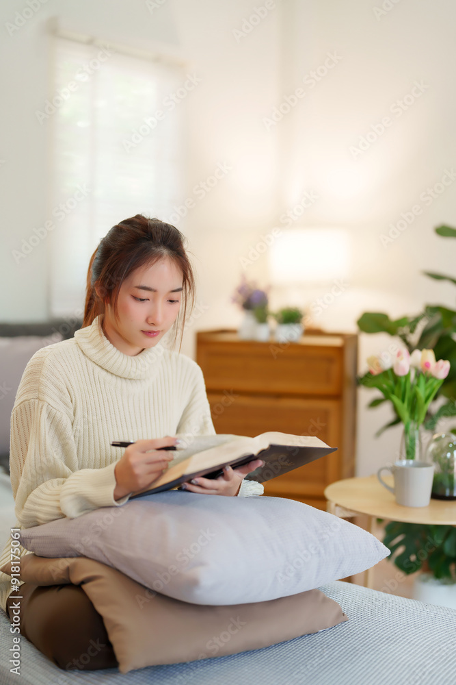 Young asian women in sweater opening the book to reading and learning about education for writing knowledge while relaxation and doing activity to spending time with slow life lifestyle at home