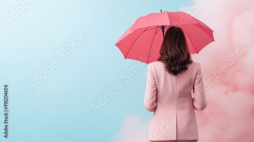 A woman dressed in a pink suit holds a matching pink umbrella while standing against a vibrant sky with pink clouds, capturing a harmonious color scheme.