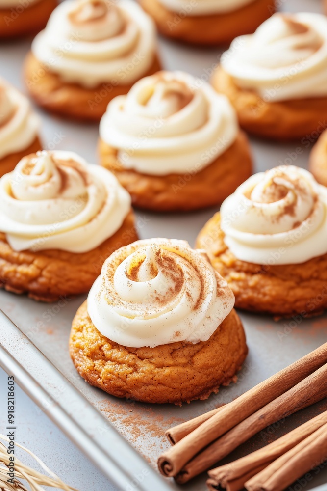 freshly baked pumpkin cookies topped with smooth cream cheese frosting, lightly dusted with cinnamon. The cookies are arranged on a baking tray freshly baked pumpkin cookies topped with smooth cream cheese frosting, lightly dusted with cinnamon. The cookies are arranged on a baking tray