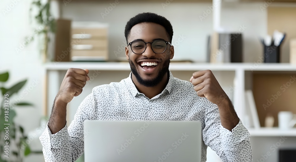 A young happy man sits at his desk with a laptop,workspace A young happy man sits at his desk with a laptop,workspace