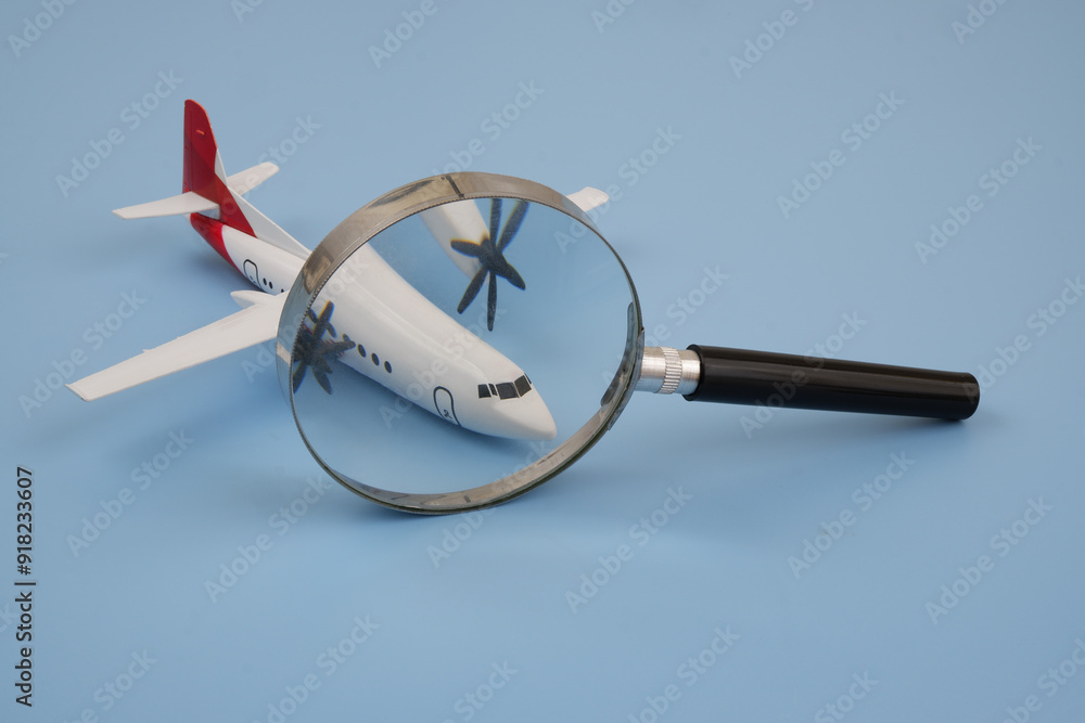 Review airlines company and check tickets price concept. Airplane under magnifying glass on blue background. Review airlines company and check tickets price concept. Airplane under magnifying glass on blue background.
