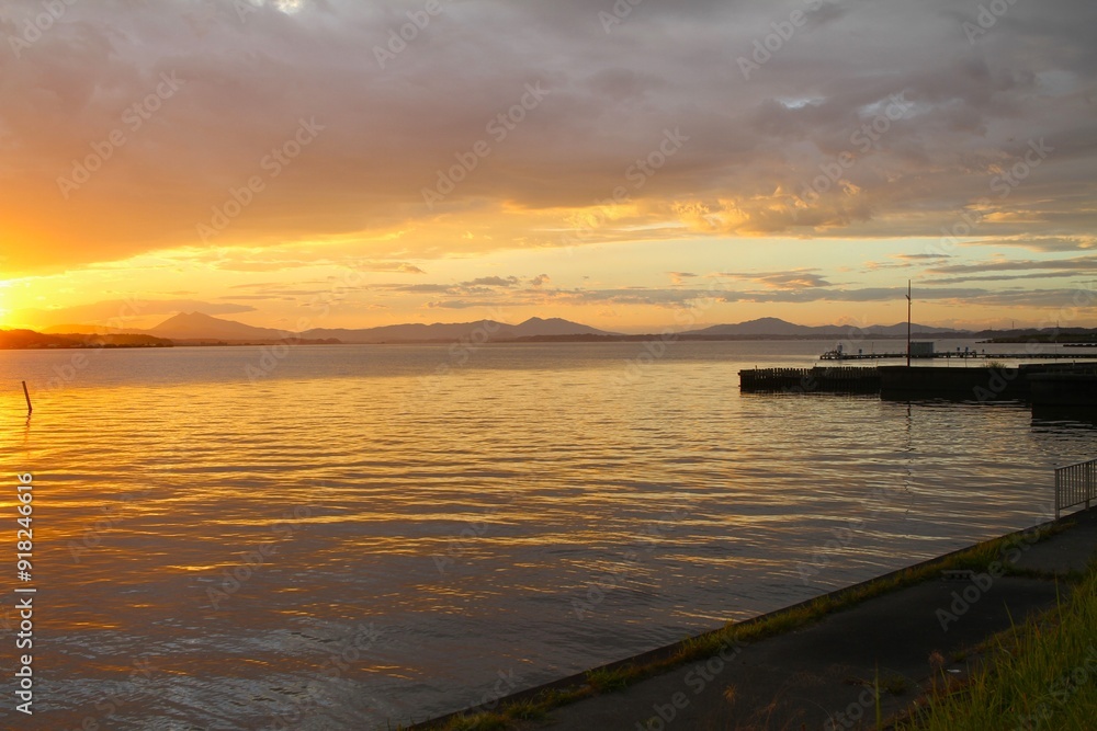 sunset on a lake pier with sky and water turning orange sunset on a lake pier with sky and water turning orange